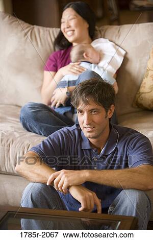 Stock Photo - Portrait of an Asian-Caucasian family sitting on sofa and the floor. Fotosearch