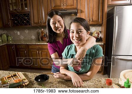 Portrait of an Asian mother embracing her Asian-Caucasian daughter in the kitchen View Large Photo Image Stock Image - Portrait of an Asian mother embracing her Asian-Caucasian daughter in the kitchen. Fotosearch