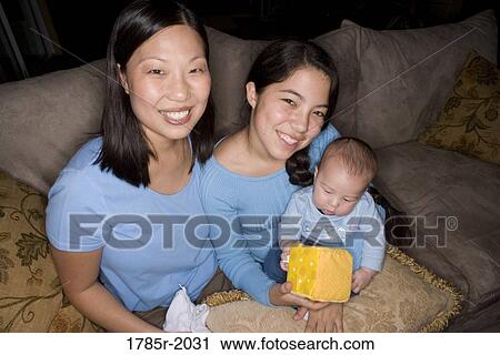 Stock Image - Portrait of an Asian mother with her Asian-Caucasian teenage daughter and infant boy. Fotosearch