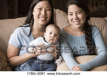 Stock Image - Portrait of an Asian mother with her Asian-Caucasian teenage daughter and infant boy. Fotosearch