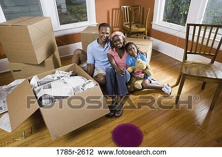 Stock Image - Portrait of family sitting by moving boxes. Fotosearch