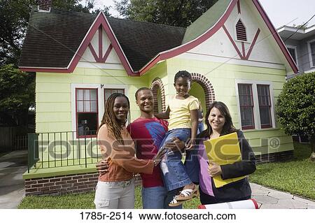 Picture - Portrait of family standing outside house with real estate broker. Fotosearch