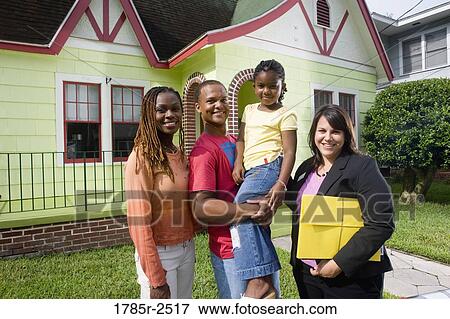 Stock Photo - Portrait of family standing outside house with real estate broker. Fotosearch
