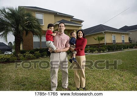 Stock Photography - Portrait of family standing outside house. Fotosearch