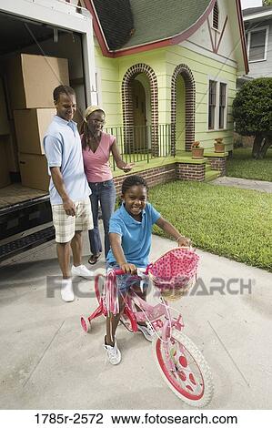 Portrait of girl riding bicycle with parents standing by moving truck View Large Photo Image Stock Image - Portrait of girl riding bicycle with parents standing by moving truck. Fotosearch