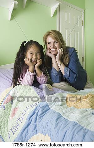 Portrait of mother and daughter sitting on bed View Large Photo Image Picture - Portrait of mother and daughter sitting on bed. Fotosearch