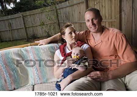 Portrait of smiling parents with baby sitting in backyard View Large Photo Image Stock Image - Portrait of smiling parents with baby sitting in backyard. Fotosearch