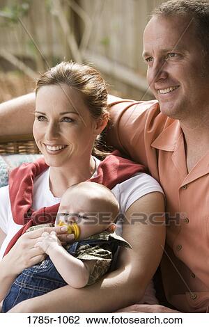 Stock Image - Portrait of smiling parents with baby outdoors. Fotosearch
