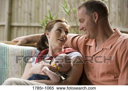 Stock Photography - Portrait of smiling parents with baby outdoors. Fotosearch