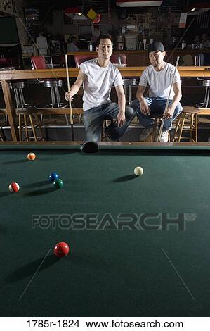 Portrait of two men in jeans and t-shirts sitting in front of billiards table View Large Photo Image Picture - Portrait of two men in jeans and t-shirts sitting in front of billiards table. Fotosearch