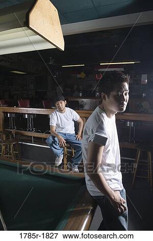 Portrait of two men in jeans and t-shirts standing beside billiards table View Large Photo Image Stock Photo - Portrait of two men in jeans and t-shirts standing beside billiards table. Fotosearch