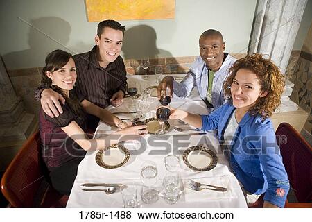 Portrait of two smiling young couples sitting at a restaurant table drinking wine View Large Photo Image Stock Photo - Portrait of two smiling young couples sitting at a restaurant table drinking wine. Fotosearch