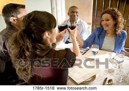 Portrait of two smiling young couples sitting at a restaurant table toasting wine View Large Photo Image Stock Photo - Portrait of two smiling young couples sitting at a restaurant table toasting wine. Fotosearch