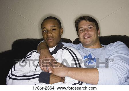 Portrait of two young men, a gay couple, sitting on a sofa View Large Photo Image Picture - Portrait of two young men, a gay couple, sitting on a sofa. Fotosearch