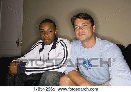 Stock Photography - Portrait of two young men sitting on a sofa. Fotosearch