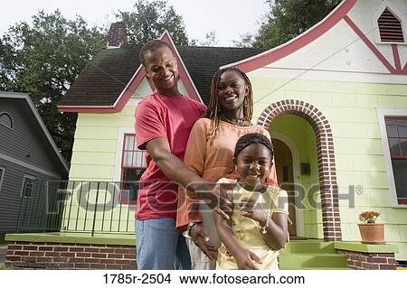 Portrait of young family standing in front of house View Large Photo Image Picture - Portrait of young family standing in front of house. Fotosearch