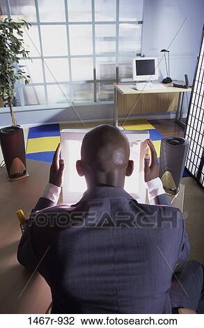 Rear view of a businessman sitting in front of a computer View Large Photo Image Stock Image - Rear view of a businessman sitting in front of a computer. Fotosearch
