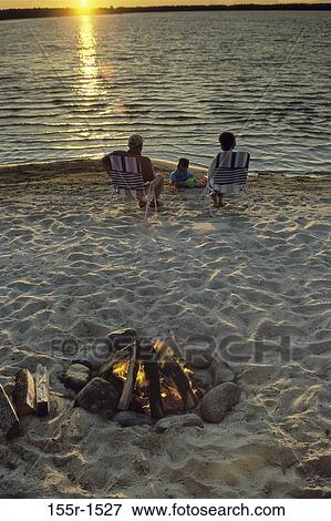 Rear view of a father and mother sitting on the beach with their son View Large Photo Image Stock Photo - Rear view of a father and mother sitting on the beach with their son. Fotosearch