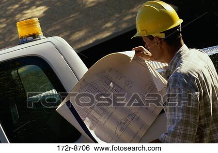 Rear view of a male architect looking at a blueprint View Large Photo Image Stock Photograph - Rear view of a male architect looking at a blueprint. Fotosearch