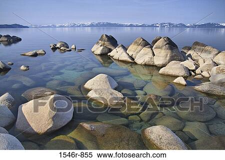 Stock Photography - Rocky shoreline of a lake with mountains in the background, East Shore, Lake Tahoe, Nevada, USA. Fotosearch