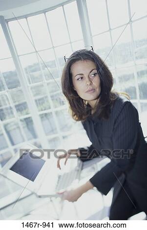 Side profile of a businesswoman sitting in front of a laptop View Large Photo Image Stock Image - Side profile of a businesswoman sitting in front of a laptop. Fotosearch