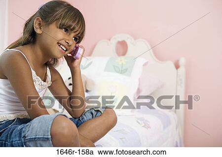 Stock Image - Side profile of a girl talking on a mobile phone. Fotosearch
