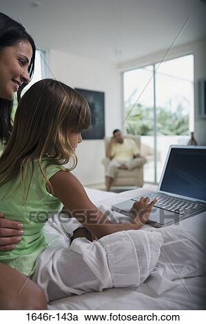 Side profile of a girl using a laptop with her mother View Large Photo Image Stock Image - Side profile of a girl using a laptop with her mother. Fotosearch