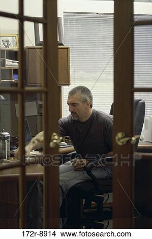 Picture - Side profile of a mid adult man sitting in an office. Fotosearch
