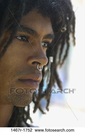 Stock Image - Side profile of a young man wearing a nose ring. Fotosearch