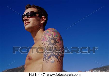Side profile of a young man with a tattoo on his arm View Large Photo Image Stock Photo - Side profile of a young man with a tattoo on his arm. Fotosearch