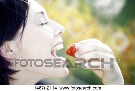 Side profile of a young woman eating a strawberry View Large Photo Image Picture - Side profile of a young woman eating a strawberry. Fotosearch