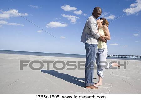Side view of a romantic young couple embracing on beach View Large Photo Image Stock Photography - Side view of a romantic young couple embracing on beach. Fotosearch