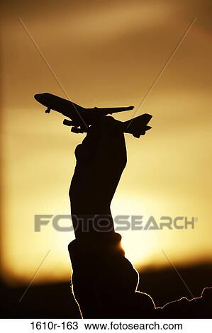 Silhouette of a person's hand holding a model airplane View Large Photo Image Stock Image - Silhouette of a person's hand holding a model airplane. Fotosearch