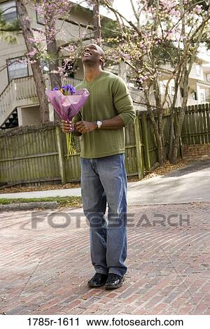 Smiling young man standing on street holding bouquet of flowers View Large Photo Image Stock Image - Smiling young man standing on street holding bouquet of flowers. Fotosearch