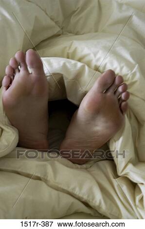 Soles of a person's feet lying on a bed View Large Photo Image Stock Photo - Soles of a person's feet lying on a bed. Fotosearch