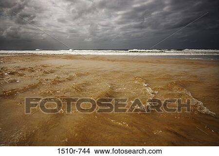 Picture - Stormy sea and flood waters at beach. Fotosearch