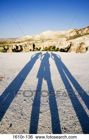 Tall shadows of three people on a landscape, Cappadocia, Turkey View Large Photo Image Stock Photograph - Tall shadows of three people on a landscape, Cappadocia, Turkey. Fotosearch