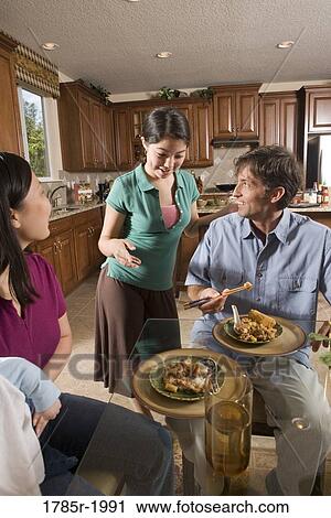 Stock Image - Teenage Asian-Caucasian girl serving a home-cooked Asian dinner to her family. Fotosearch