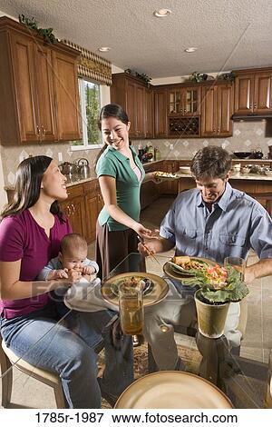 Stock Photo - Teenage Asian-Caucasian girl serving a home-cooked Asian dinner to her family. Fotosearch