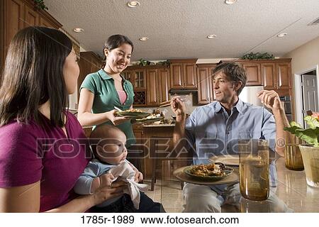 Stock Photo - Teenage Asian-Caucasian girl serving a home-cooked Asian dinner to her family. Fotosearch