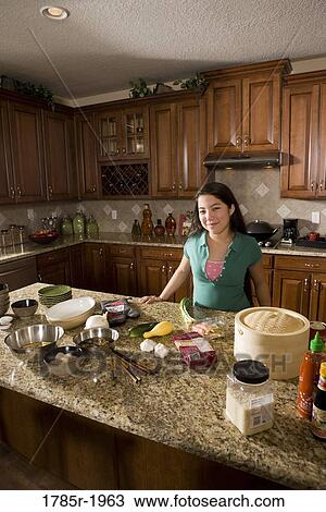 Teenage girl in kitchen with ingredients for Asian-style dish View Large Photo Image Stock Image - Teenage girl in kitchen with ingredients for Asian-style dish. Fotosearch
