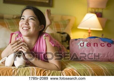 Teenage girl in pajamas lying on her bed dreamily clutching a pair of ballet slippers View Large Photo Image Stock Photo - Teenage girl in pajamas lying on her bed dreamily clutching a pair of ballet slippers. Fotosearch