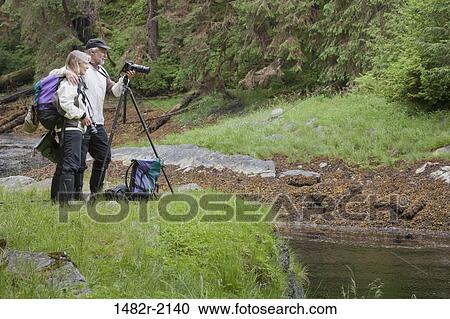 Stock Image - Tourists taking a picture in a forest, Naha Bay, Alaska, USA. Fotosearch