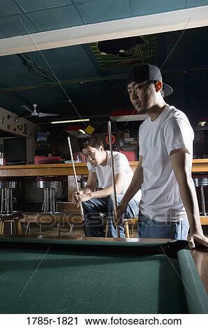 Two Asian men in jeans and t-shirts playing billiards View Large Photo Image Stock Image - Two Asian men in jeans and t-shirts playing billiards. Fotosearch