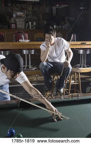 Two Asian men in jeans and t-shirts playing billiards View Large Photo Image Stock Photo - Two Asian men in jeans and t-shirts playing billiards. Fotosearch