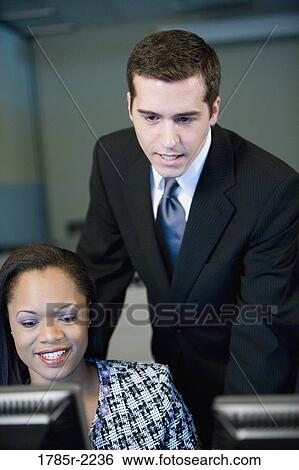 Two business people looking at a computer monitor View Large Photo Image Stock Photograph - Two business people looking at a computer monitor. Fotosearch