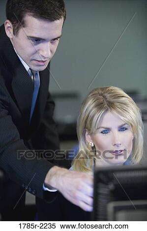 Two business people looking at a computer monitor View Large Photo Image Stock Photography - Two business people looking at a computer monitor. Fotosearch