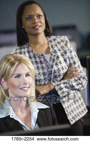 Picture - Two business women in office looking up. Fotosearch