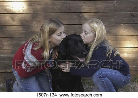 Picture - Two girls kissing a dog. Fotosearch
