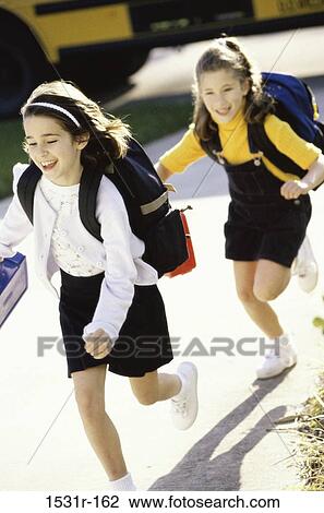 Stock Image - Two girls running with school bags on their backs. Fotosearch